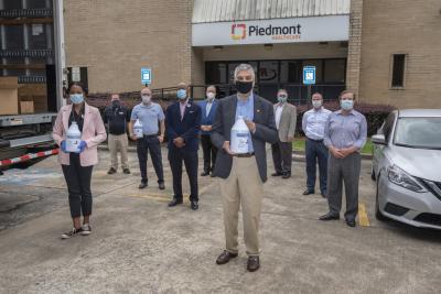 Here, many participants in the effort that re-made hand sanitizer using fuel-grade ethanol on its first day of delivery. The volunteers will donate 7,000 gallons of Han-I-Size White and Gold to hospitals and nursing homes across the country. In front, Dr. Chaouki Abdallah, Executive Vice President for Research, congratulates the group on its success. Image courtesy Georgia Tech News Center website