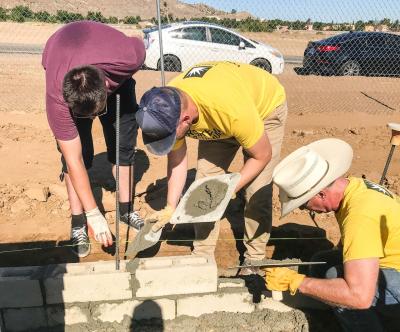 Volunteers worked together cementing blocks to construct a perimeter wall that will be part of a 56 home community for low-income veterans.