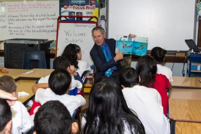 Subaru of America President & CEO Tom Doll reads to Harry C. Sharp Elementary School students, following Subaru book donation.