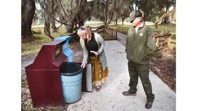 Keep Golden Isles Beautiful Executive Director Lea King-Badyna and Fort Frederica National Park Site Manager Steve Theus check out one of the trash and recycling bins at the park. KGIB is assisting with containing litter during the current government shutdown. Photo courtesy of Bobby Haven, The Brunswick News.