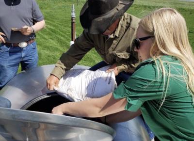 Kate Indreland and her dad, Roger Indreland, pour salt into a spray solution to add much-needed sodium into the mixture of fish hydrolysate and vermicast, which will benefit the soil in their fields.