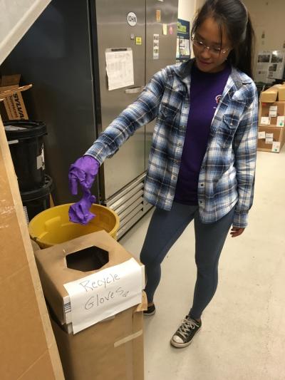 Michelle Chen, a guest student at the Woods Hole Oceanographic Institution, drops her used lab gloves into a bin for recycling by Kimberly-Clark Professional’s RightCycle Program.