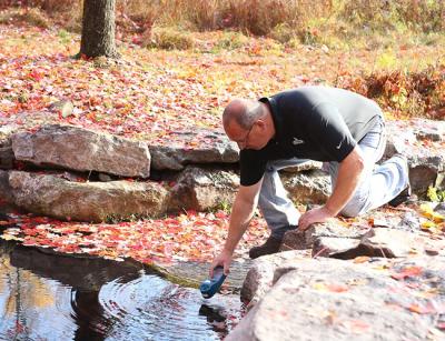 Spring Maintenance Supervisor John Leibold collecting a water sample from a natural spring at the Greenwaltz Springs site to check the conductivity of the water