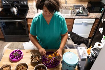 Bridgett Jeffries prepares meals for her canine customers at her home-based dog daycare and boarding business.