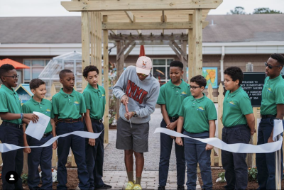 13-time Grammy-winning singer-producer Pharrell Williams cuts the ribbon to reveal the expanded community garden at Seatack Elementary School, Virginia Beach which Timberland volunteers helped to revitalize.