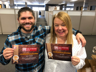 Timberland’s Jason Blades and Jill Holt plan events to engage the company’s employees in community service. They show off their 40s club certificates they received for serving all of their available service hours.