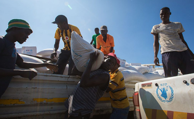 WFP’s local partner staff helps unload corn, beans and vegetable oil from one of three WFP food trucks. Source: Guido Dingemans