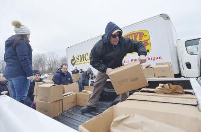 Tim Schnapp joins volunteers as they load turkeys and food boxes to be distributed to area residents Thursday during the third annual Holiday Food Sharing Program at Southwest Michigan Community Action Agency's warehouse in downtown Benton Harbor. The program, sponsored by the city of Benton Harbor, the PGA of America and Whirlpool Corp., collects and distributes 400 turkeys to residents and families in need during the holiday season. Don Campbell / HP staff