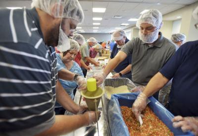Erich Kirchner, right, joins fellow Whirlpool Corp. employees as they put together nutritional packets for the non-profit organization Pack Away Hunger. Photo credit: Herald-Palladium
