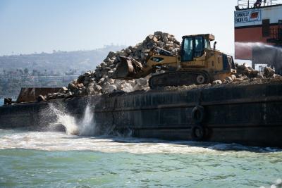 A large crane is used to pick up and drop organic quarry rocks into 38 feet of water for the expansion of the Wheeler North Reef.