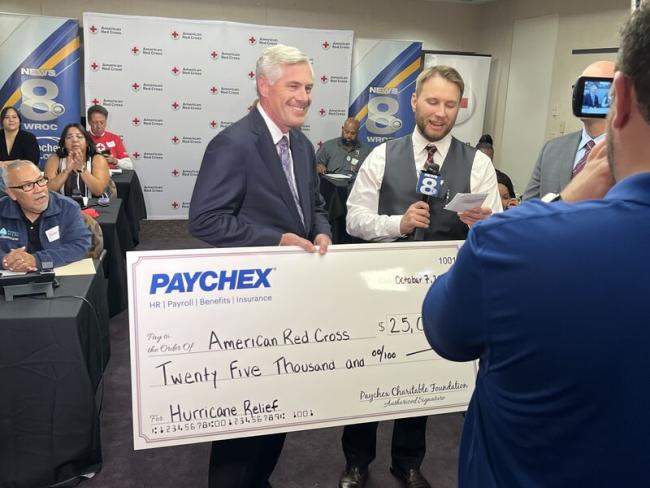 Man holding big check of donation from Paychex