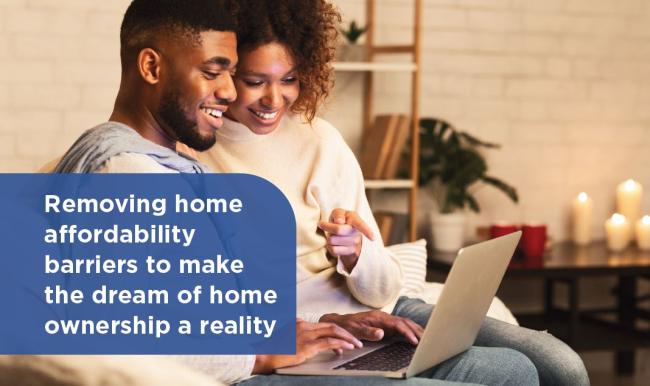 Man and woman smiling in front of computer with text overlaid that says, "Removing home affordability barriers to make the dream of home ownership a reality"