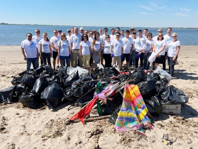 Members of Community Offshore Wind stand on the beach, showing the trash collected during the event