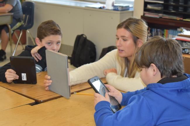 a teacher reads to students from a tablet