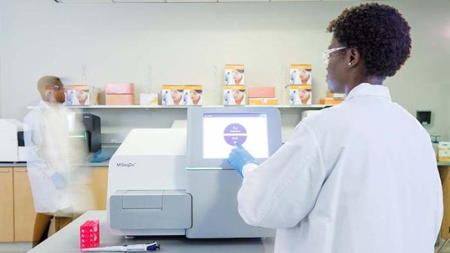 Female lab scientist working with an Illumina gene sequencing machine.