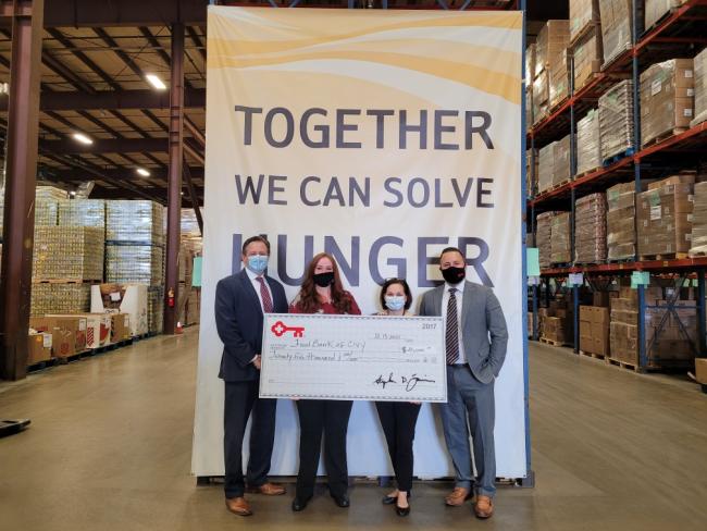 Together we can solve hunger banner; 4 members of KeyBank team (2 women and 2 men) are holding a check for $25,000.