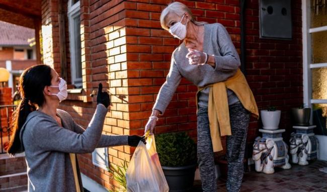 Woman delivering groceries to older woman