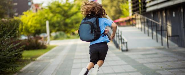 child in a blue shirt and backpack jumping in the air