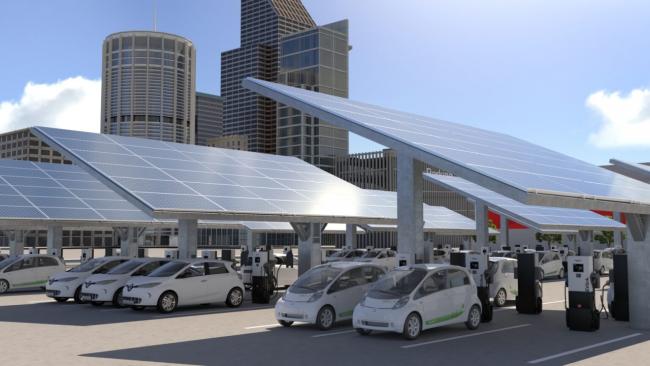 Electric cars pictured below solar panels and next to charging stations