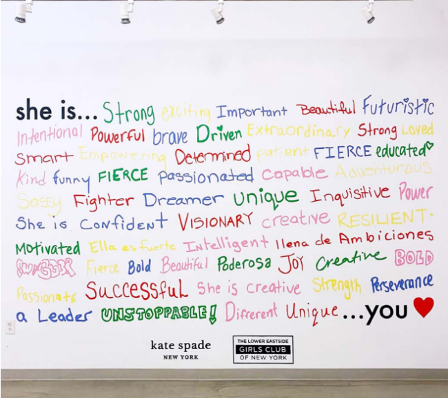 A mural at the Lower East Side Girls Club that says "she is" with many positive adjectives listed in marker below it