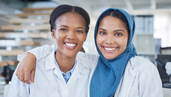 Two women in lab coats smiling