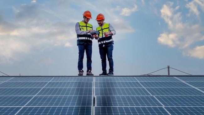 Workers standing on roof with Solar Panels