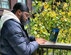 Jeremiah on a balcony writing on laptop