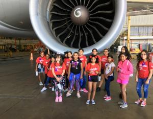 Class of girls in front of jet engine