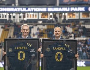 Alan Bethke, senior vice president of marketing for Subaru of America, and Tim McDermott, president of the Philadelphia Union, celebrate Subaru Park becoming the first soccer stadium in Major League Soccer to achieve zero landfill status on Oct. 23, 2021. Two people holding up soccer jerseys with the words "Landfill 0"