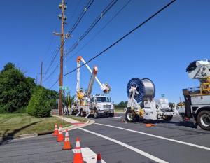 Photo showing PSEG crews updating power lines. Trucks with wiring and a cherry picker are shown.