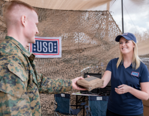 Woman from USO handing something to a soldier