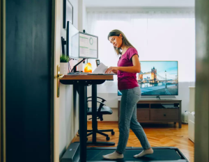 Woman at standing desk with walking treadmill underneath 