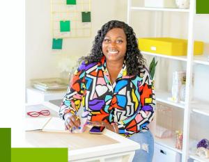 Wayneisha Walker in a colorful shirt, sitting at a desk with an open notebook