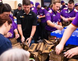 FedEx volunteers assemble crates of care packages