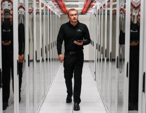 A person walking down a hall lined with large servers on both sides