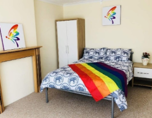 safe house bedroom with a rainbow flag on the bed and rainbow art on the walls