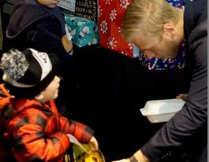LA Kings defenseman Colin Folin presents a toy to a child at the LA Kings Adopt-A-Family event at STAPLES Center on December 9, 2017.