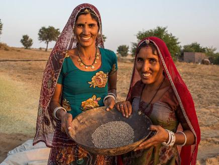 two people holding a container of seeds outside