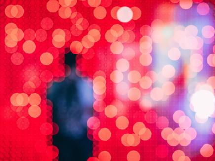 unfocused silhouette of a person in front of a field of pixelated red and blue lights