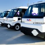 Row of white FedEx BrightDrop vehicles