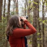 Audubon South Carolina’s Jennifer McCarthey Tyrrell, in orange sweater, looking through binoculars