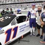 Mayra Hernandez, Jesse Iniguez and Denny Hamlin stand next to the FedEx 11 race car