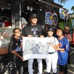 kids and one adult posing next to Tai's Taco Truck holding a Mets! sign