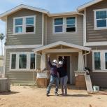 Cynthia E., her husband Valdemar C. pose outside of their new home by Habitat