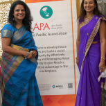 Two women next to Asia Pacific Association sign 