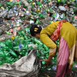 Woman in front of large pile of plastic bottles