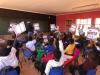 Classroom full of students in Africa are holding up a 3M Science at Home booklet. 