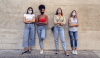 four women standing against a wall