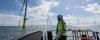 Worker in high-visibility safety gear overlooking off-shore wind turbines