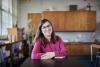 a smiling woman in glasses and a pink shirt